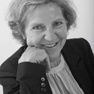 Annette Schimmel | © BIS/Jens Meier Portrait einer Frau, die mit ihren Kopf gestützt auf den Arm in die Kamera lächelt | © BIS/Jens Meier