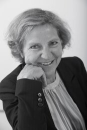 Annette Schimmel | © BIS/Jens Meier Portrait einer Frau, die mit ihren Kopf gestützt auf den Arm in die Kamera lächelt | © BIS/Jens Meier